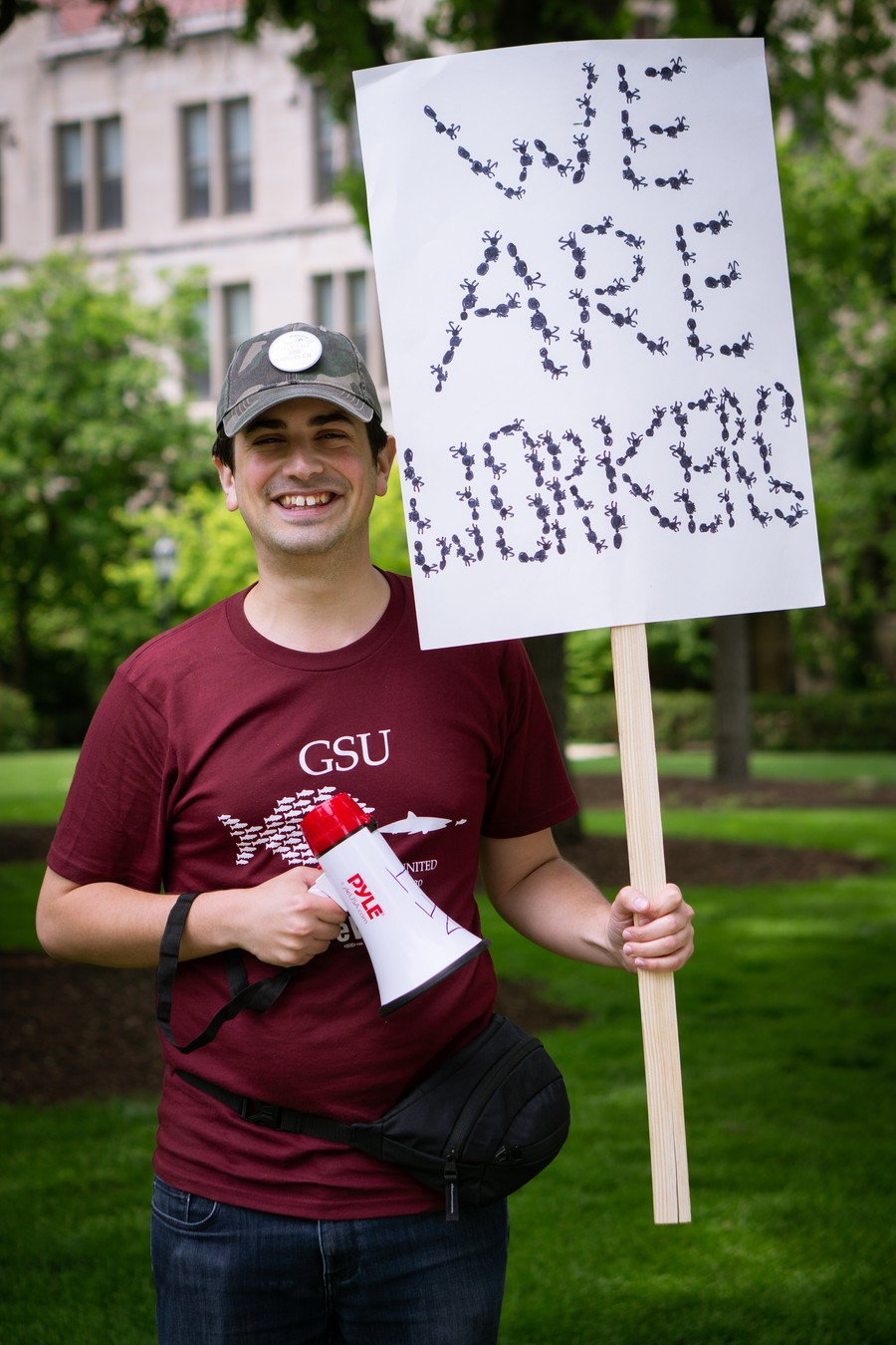 PhD candidate in evolutionary biology Ben Blanchard holds a sign reading "We Are Workers," spelled in ants.